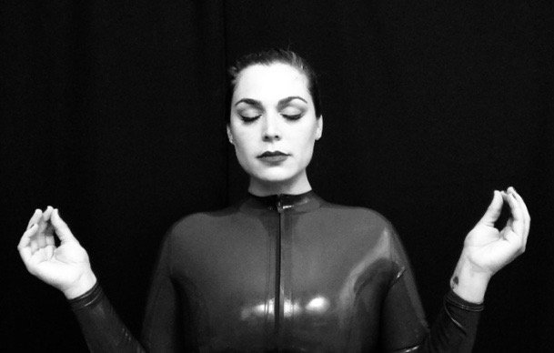 dominatrix meditating in latex catsuit